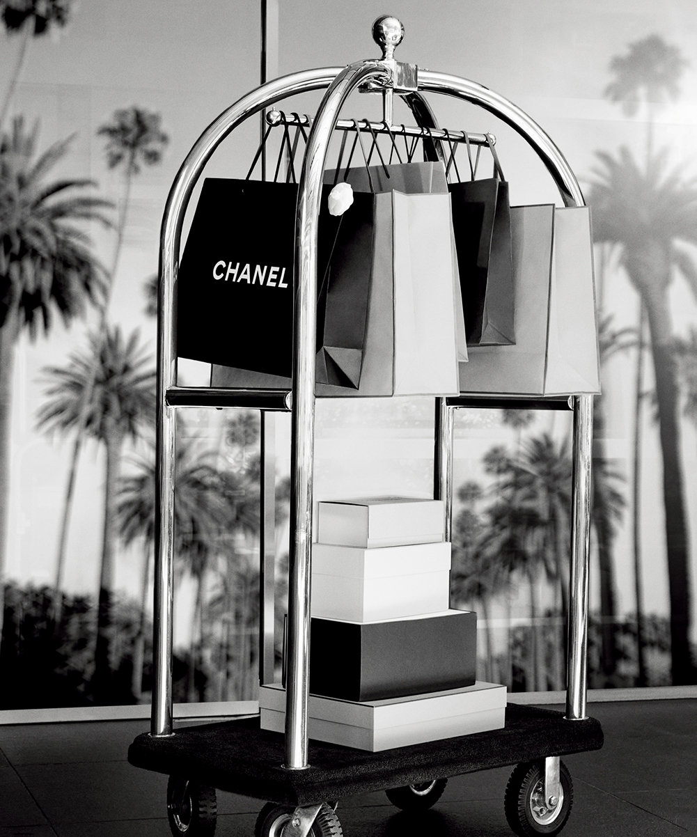 Chanel and various shopping bags on a hotel luggage cart